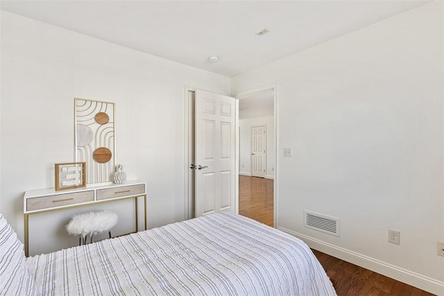 bedroom with visible vents, baseboards, and wood finished floors