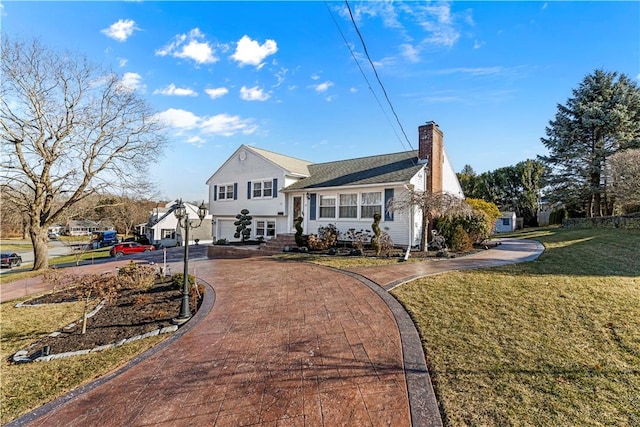 split level home with a chimney, aphalt driveway, and a front yard