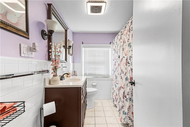 bathroom with toilet, a wainscoted wall, tile walls, vanity, and tile patterned floors