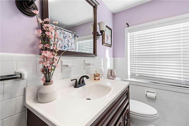 full bathroom featuring tile walls, a wainscoted wall, vanity, and toilet