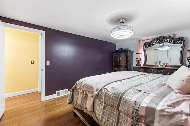 bedroom with light wood finished floors, baseboards, and visible vents