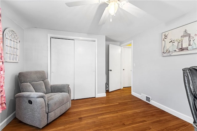 sitting room featuring a ceiling fan, visible vents, baseboards, and wood finished floors