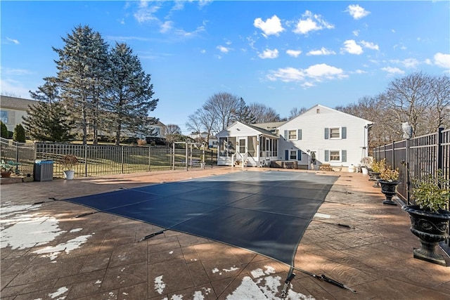 view of swimming pool featuring a sunroom, fence, and a patio