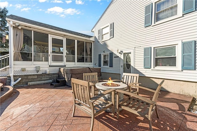 view of patio / terrace featuring an outdoor fire pit and a sunroom