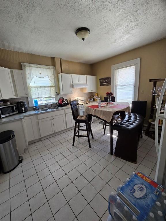 kitchen featuring light countertops, white cabinetry, a sink, and under cabinet range hood