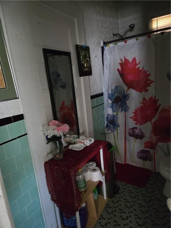 bathroom featuring toilet, curtained shower, tile walls, and tile patterned floors