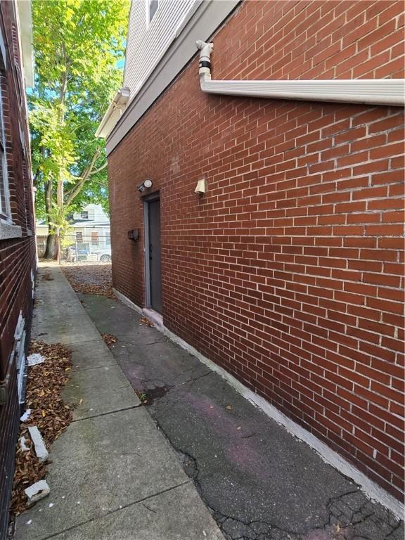 view of side of property featuring fence and brick siding