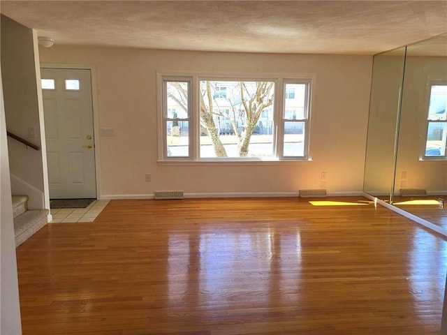 entrance foyer with a textured ceiling, wood finished floors, stairs, and baseboards