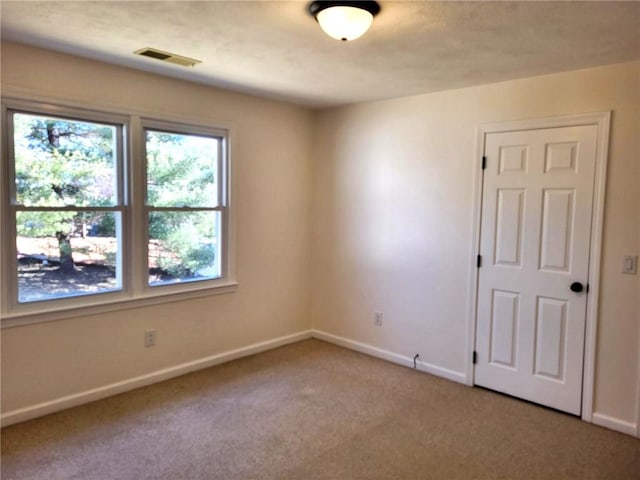 empty room with visible vents, baseboards, and light colored carpet