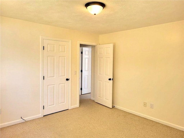 empty room featuring light carpet, baseboards, and a textured ceiling