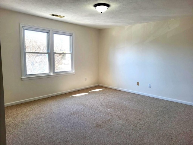 unfurnished room with carpet, visible vents, a textured ceiling, and baseboards