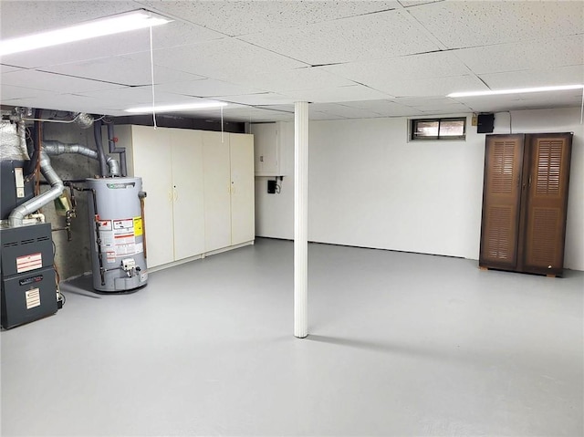 below grade area featuring a paneled ceiling and water heater