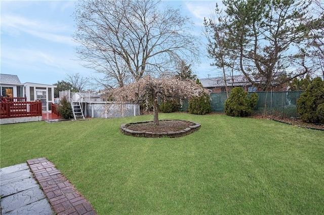 view of yard with a deck, fence, and a sunroom