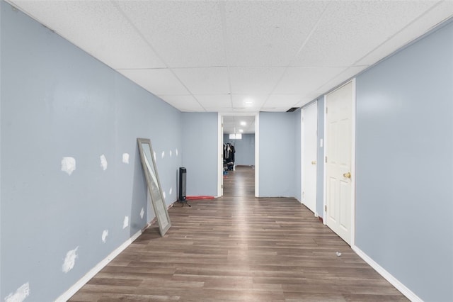 corridor featuring a drop ceiling, baseboards, and wood finished floors