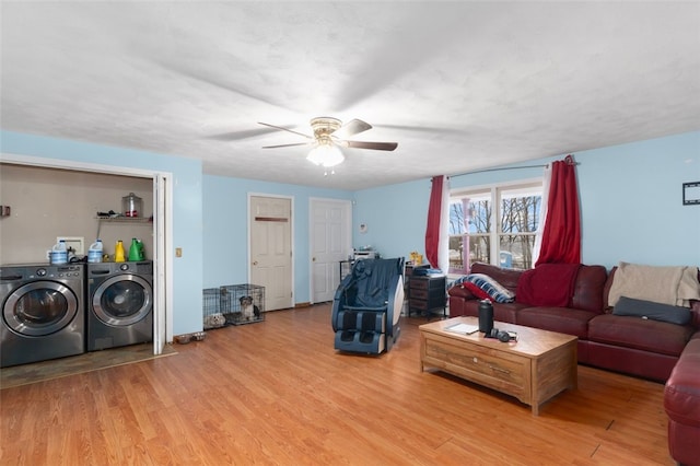 living room featuring independent washer and dryer, light wood finished floors, and ceiling fan