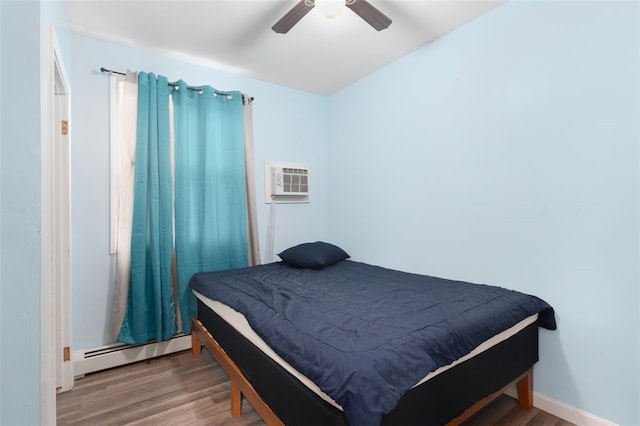 bedroom featuring a baseboard heating unit, ceiling fan, a wall mounted AC, and wood finished floors