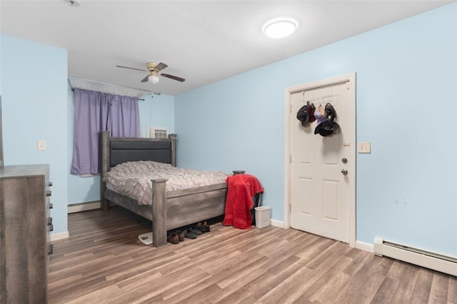 bedroom featuring baseboards, baseboard heating, and wood finished floors