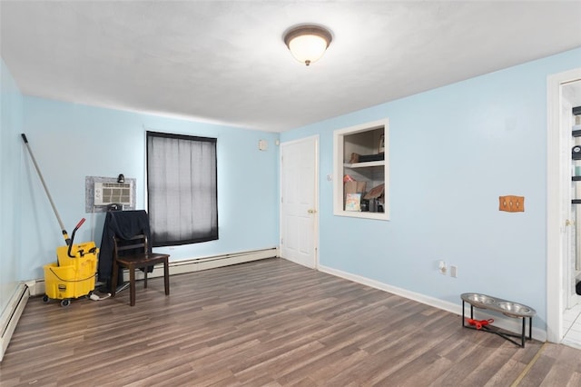 sitting room with a baseboard radiator, an AC wall unit, baseboards, and wood finished floors