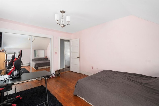 bedroom with a chandelier, a baseboard heating unit, dark wood-type flooring, and vaulted ceiling