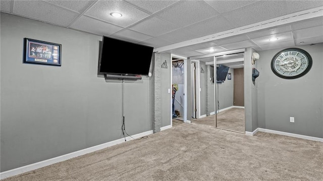 finished basement with a paneled ceiling, carpet flooring, and baseboards