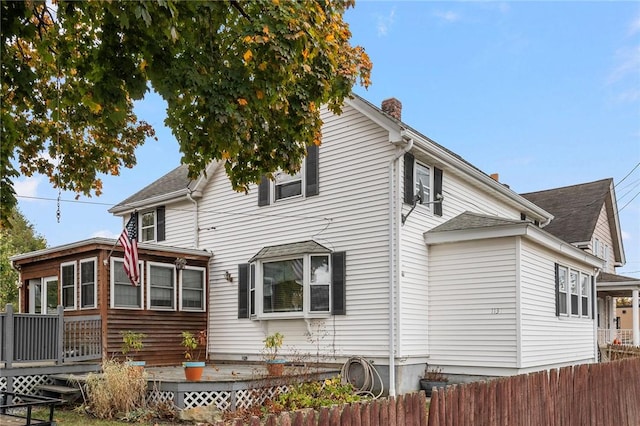 exterior space with fence, a chimney, and a wooden deck