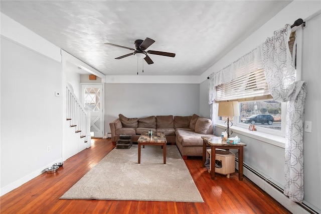 living room featuring ceiling fan, stairway, dark wood-style flooring, and a baseboard radiator