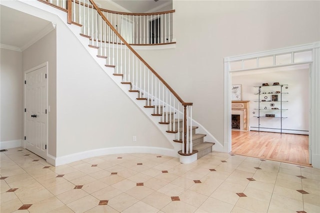 tiled entrance foyer featuring baseboards, a high ceiling, baseboard heating, and crown molding