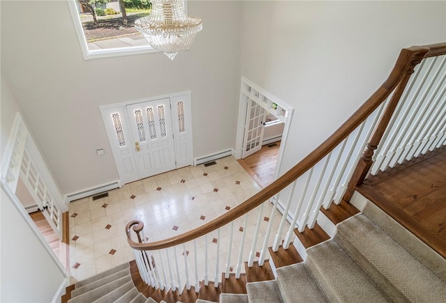 entryway with a high ceiling, stairway, a baseboard radiator, and an inviting chandelier