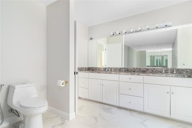 bathroom featuring marble finish floor, double vanity, a sink, and baseboards