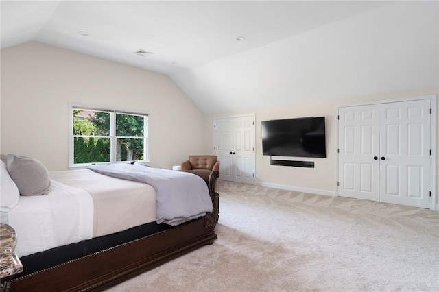 bedroom with two closets, lofted ceiling, light colored carpet, visible vents, and baseboards