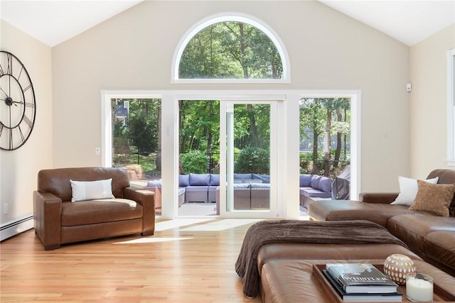 living area featuring light wood-type flooring, a healthy amount of sunlight, high vaulted ceiling, and baseboard heating