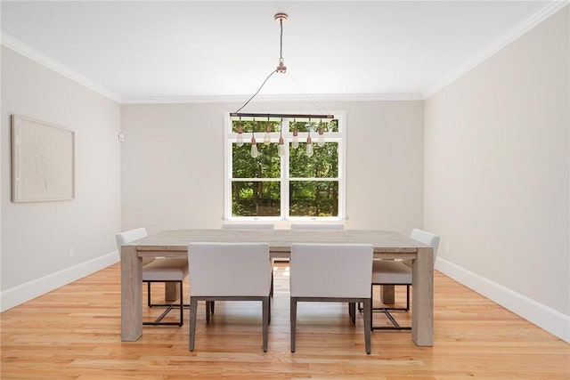 dining area featuring light wood-type flooring, crown molding, and baseboards