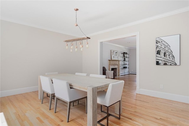 dining space featuring light wood-style floors, a fireplace, and baseboards