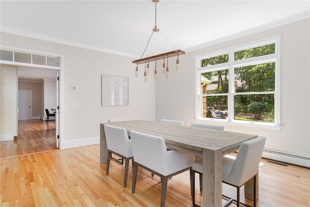 dining space featuring baseboards, a baseboard heating unit, light wood finished floors, and crown molding