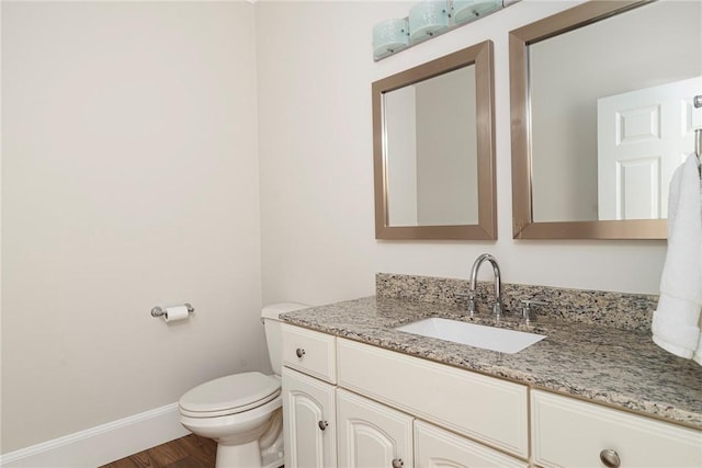 half bathroom featuring toilet, wood finished floors, vanity, and baseboards