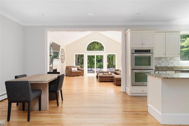 dining area with ornamental molding, lofted ceiling, light wood-style flooring, and baseboard heating