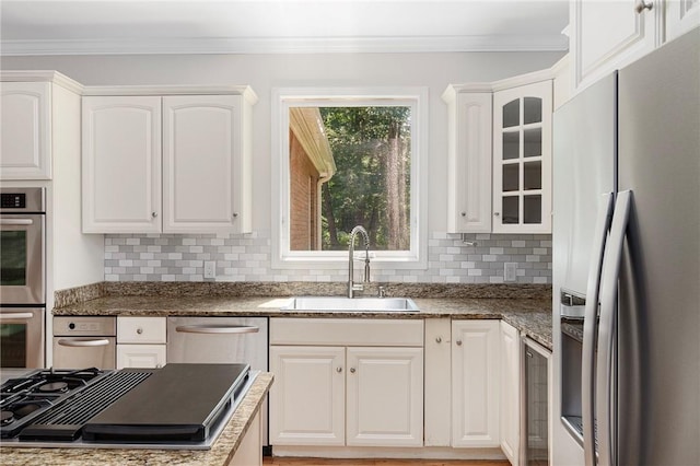 kitchen featuring stainless steel appliances, a sink, glass insert cabinets, and white cabinetry