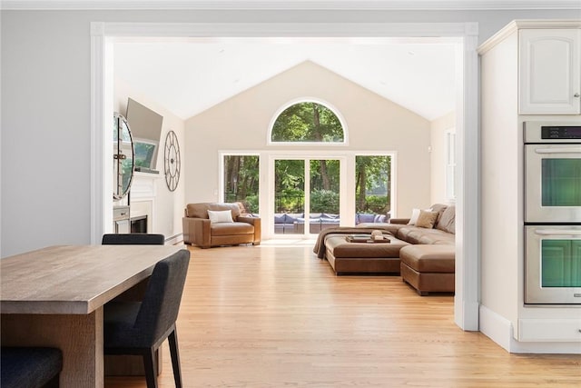 living area with light wood-style floors and high vaulted ceiling