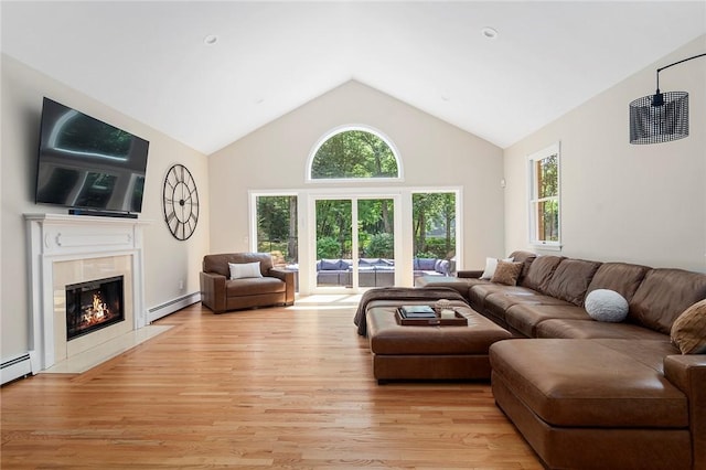 living area with a baseboard heating unit, light wood-type flooring, a fireplace, and a wealth of natural light