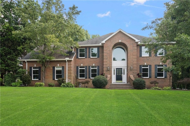 colonial house featuring a front yard and brick siding