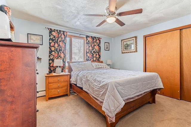 bedroom featuring a closet, light carpet, a textured ceiling, and baseboard heating