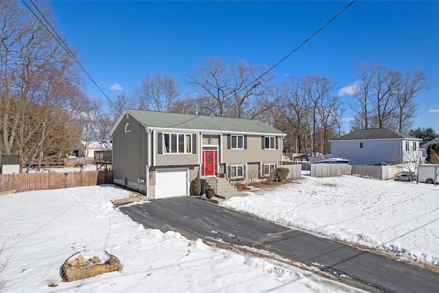 split foyer home featuring fence, driveway, and an attached garage