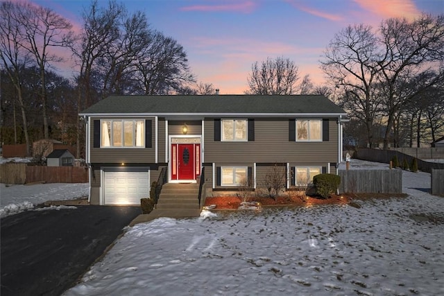 bi-level home with fence, driveway, and an attached garage