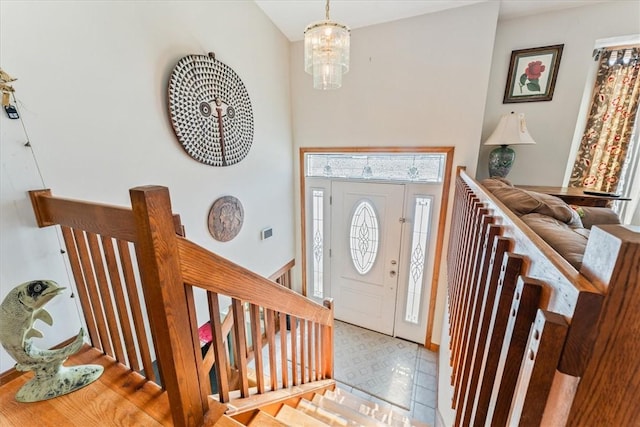 foyer entrance featuring stairs, light floors, a high ceiling, and an inviting chandelier