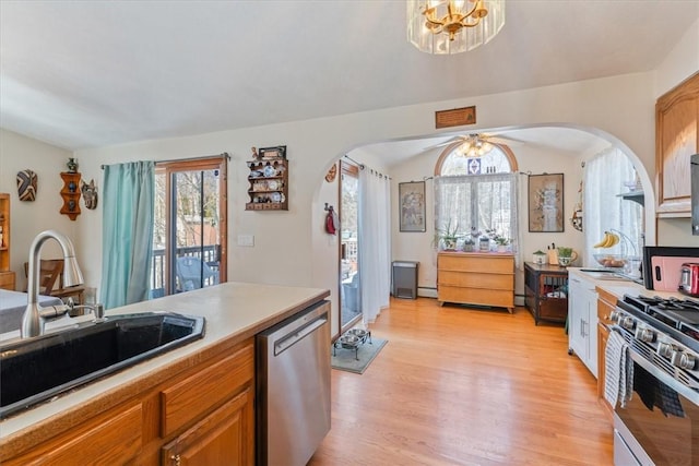 kitchen with brown cabinets, stainless steel appliances, light countertops, light wood-style floors, and a sink