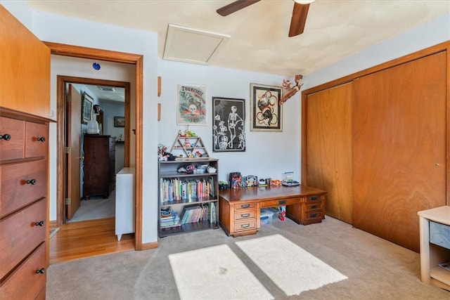 home office with a ceiling fan, attic access, and light colored carpet