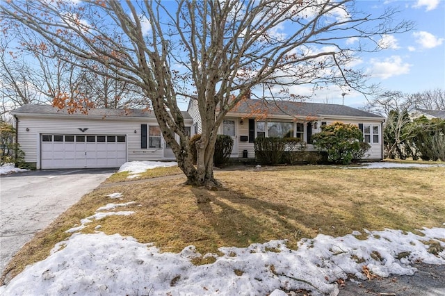 ranch-style house featuring a garage, aphalt driveway, and a lawn