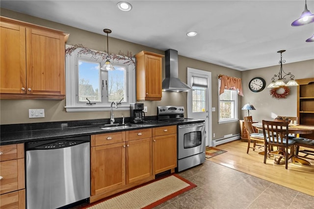 kitchen featuring a baseboard radiator, wall chimney exhaust hood, hanging light fixtures, stainless steel appliances, and a sink