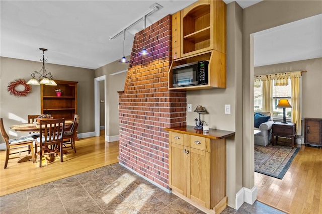 kitchen featuring dark countertops, dark wood-style floors, black microwave, pendant lighting, and track lighting