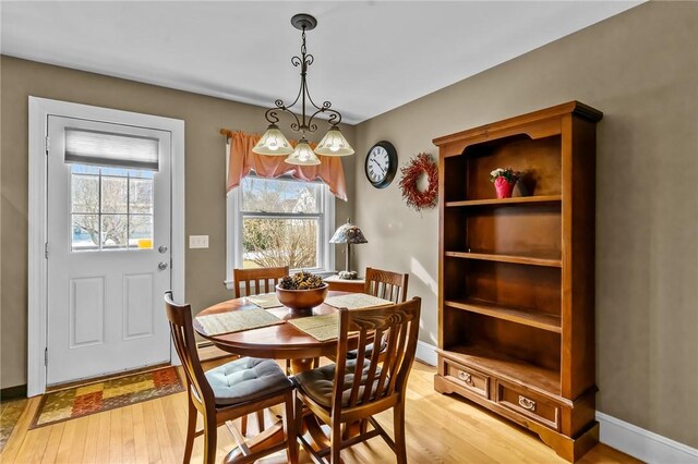 dining space with light wood-type flooring, a healthy amount of sunlight, and baseboards